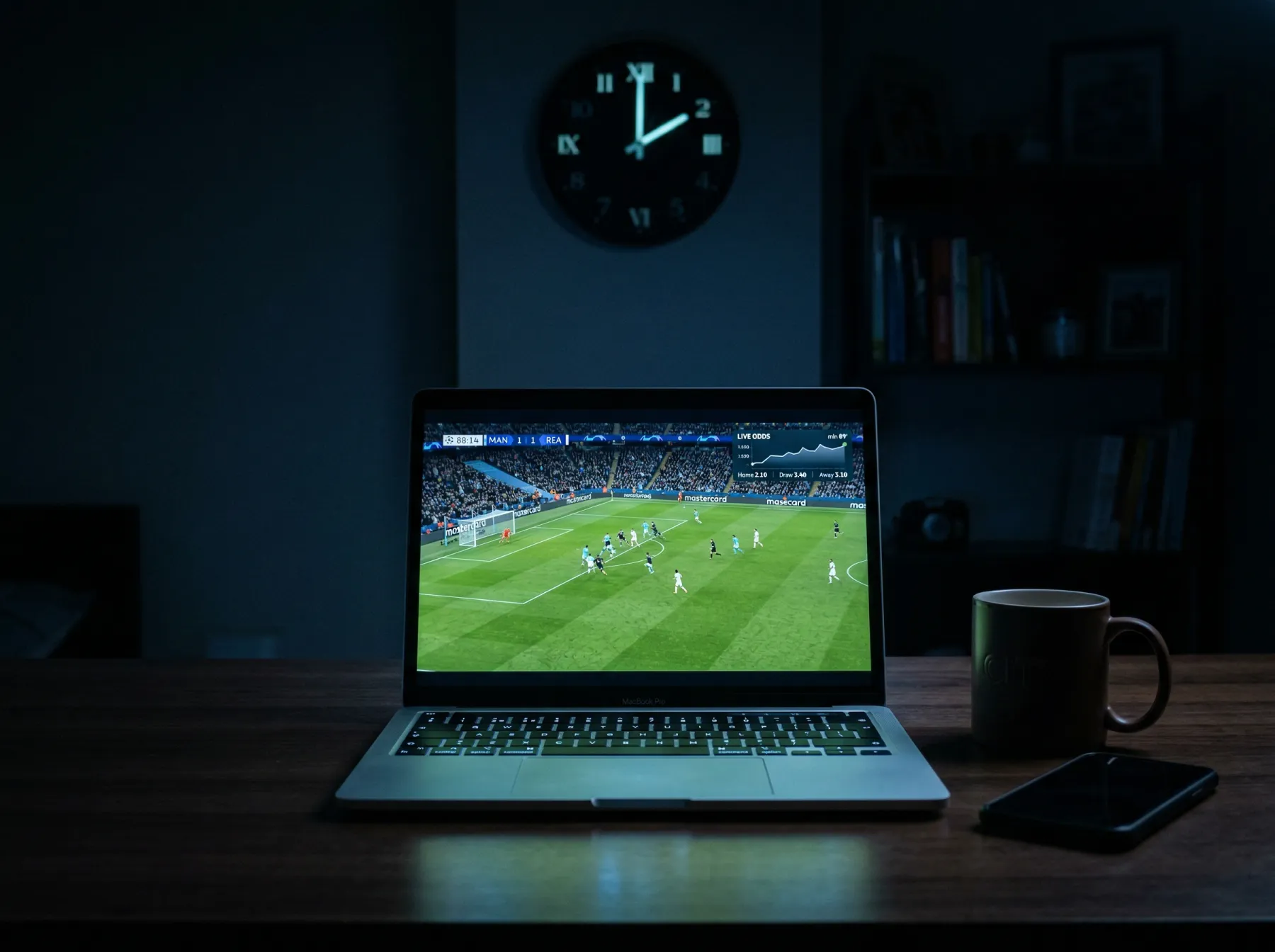 Laptop screen showing live football match odds glowing in a dark room with a clock reading 2am